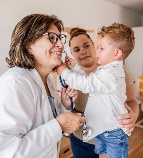 A young boy playfully using a stethoscope on a paediatrician