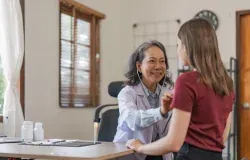 A doctor measuring an older patient's heart rate with a stethoscope