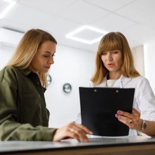 A receptionist handing forms to a patient