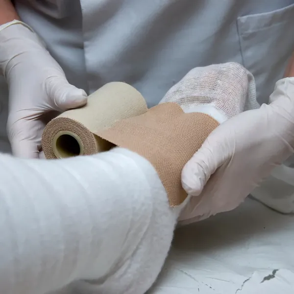 A nurse applying a bandage to a patient&rsquo;s leg