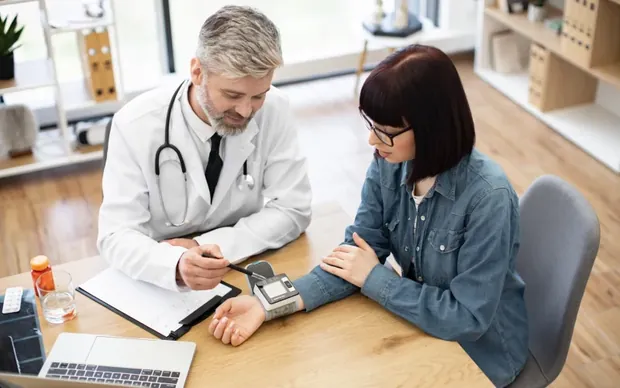 A physician checking a patient&rsquo;s blood pressure